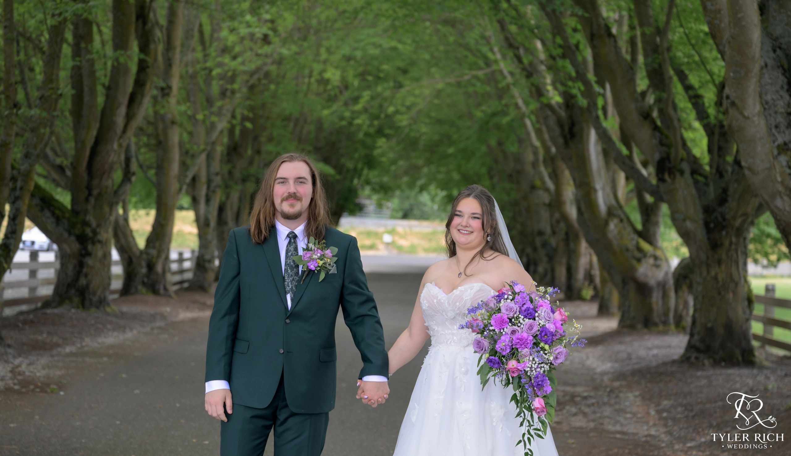 Bride and groom holding hands on a tree-lined path